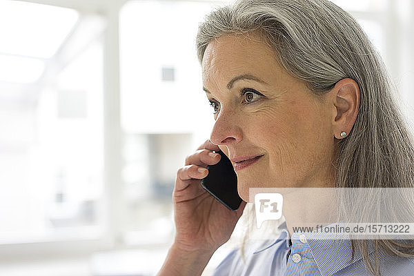 Porträt einer reifen Geschäftsfrau am Telefon im Büro