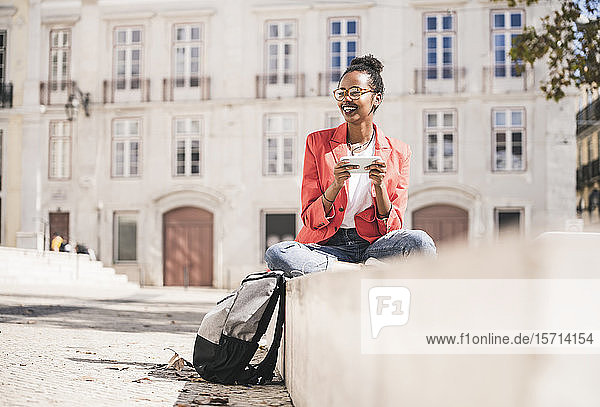 Lächelnde junge Frau mit Smartphone in der Stadt  Lissabon  Portugal