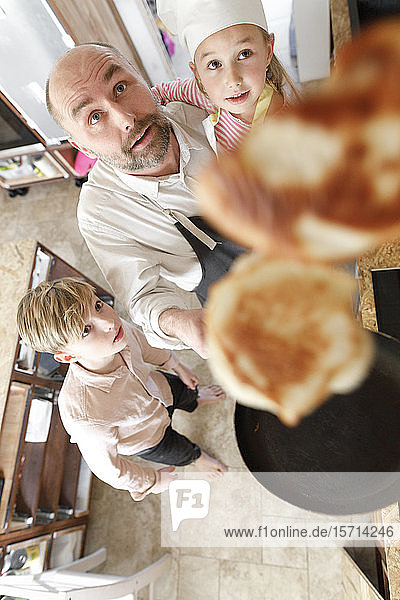 Vater und Tochter kochen in der Küche  drehen Pfannkuchen in der Luft