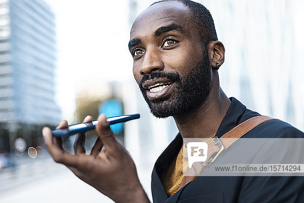 Porträt eines jungen Geschäftsmannes  der sein Handy im Freien benutzt