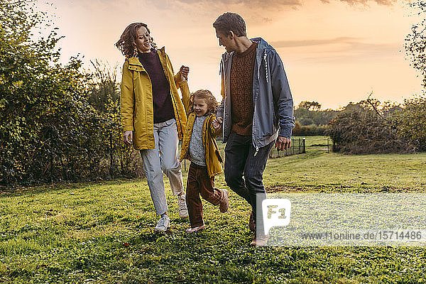 Parents with daughter walking on a meadow in autumn