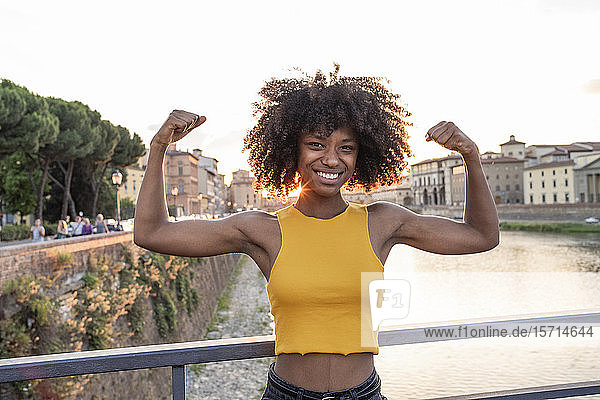 Portrait of happy young woman posing on a bridge above river Arno at sunset  Florence  Italy
