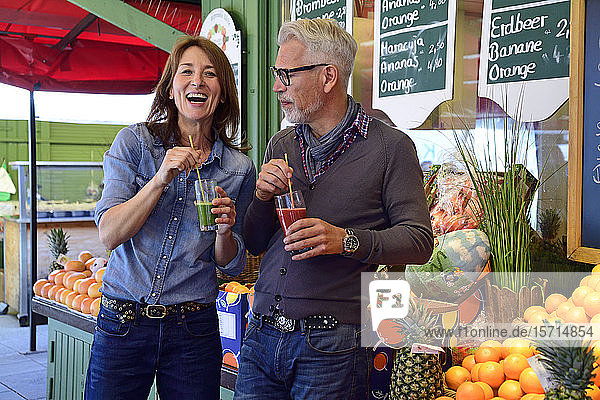 Portrait of happy mature couple drinking a healthy juice at a market stall