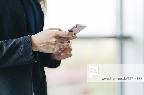 Nahaufnahme einer Geschäftsfrau bei der Benutzung eines Mobiltelefons
