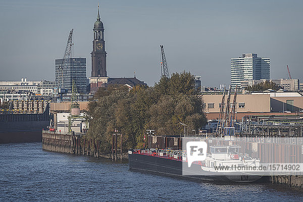 Germany  Hamburg  Container ship moored in harbor with tower of Saint Michaels Church in background