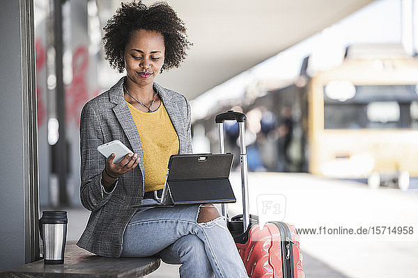 Young businesswoman using tablet and smartphone at the train station