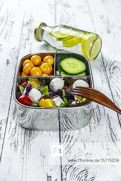 Limonadenflasche und Lunchbox mit Gurkenscheiben  Winterkirschen und Quinoa-Salat (Quinoa  Kirschtomate  Rotkohl  Zuckerschoten und Mozzarellakugeln)