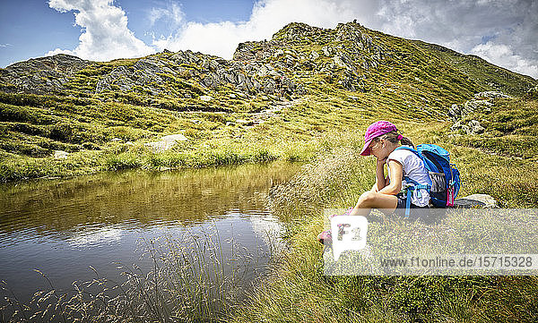 Girl having a break from hiking sitting at a mountain lake  Passeier Valley  South Tyrol  Italy