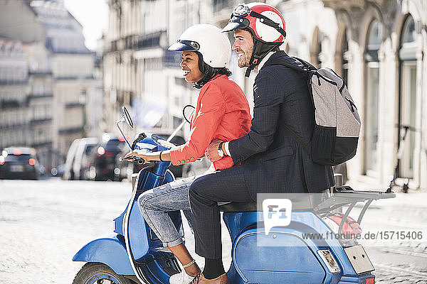 Happy young business couple riding motor scooter in the city  Lisbon  Portugal