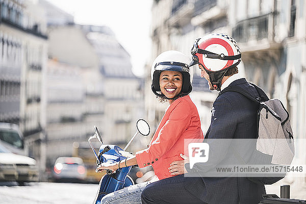 Glückliches junges Geschäftspaar auf einem Motorroller in der Stadt  Lissabon  Portugal