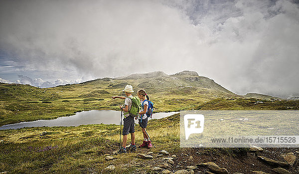 Boy and girl standing at a lake in alpine scenery  Passeier Valley  South Tyrol  Italy