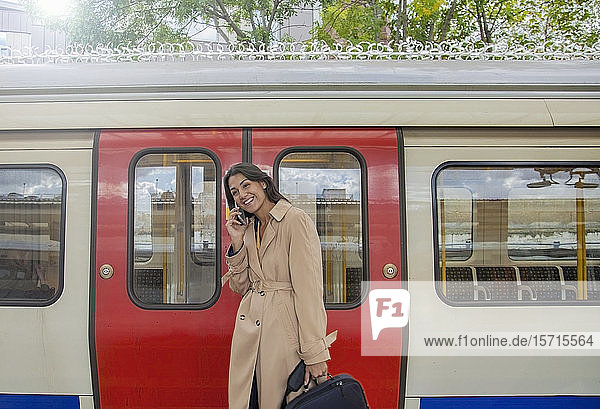 Young businesswoman using smartphone infront of commuter train