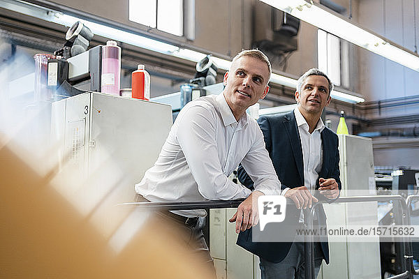 Zwei Geschäftsleute in einer Druckerei  die sich umsehen