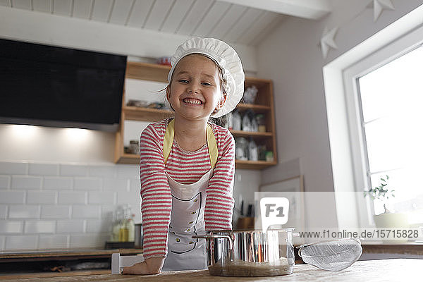 Portrait of smiling girl wearing chef's hat in the kitchen