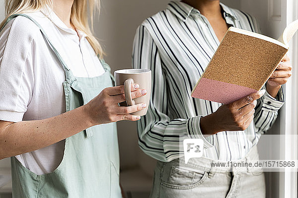 Ausschnitt von zwei Frauen mit Notebook und Tasse Kaffee