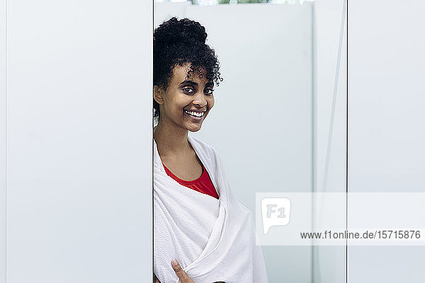 Portrait of happy young woman wrapped in a towel