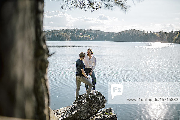 Glückliches Paar auf einem Felsen am Seeufer stehend  Forstsee  Kärnten  Österreich
