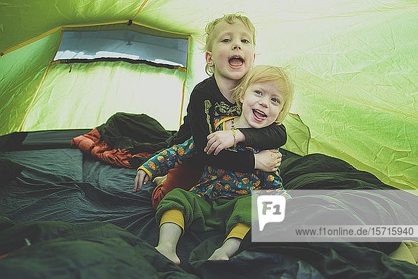 Porträt von Geschwistern  die zusammen in einem Zelt spielen