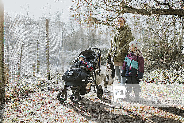 Mother with children and border collie during forest walk in autumn