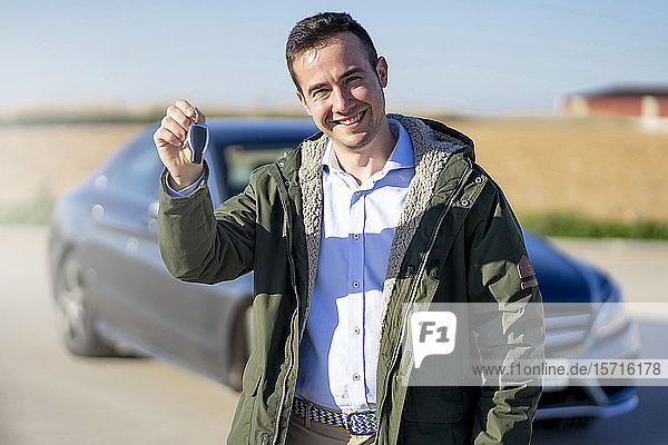 Porträt eines lächelnden jungen Geschäftsmannes mit Autoschlüssel