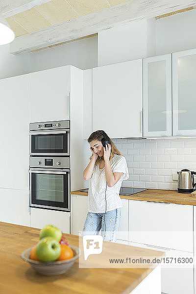 Weibliche Teeangerin mit Kopfhörern in der Küche