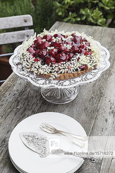 Cake stand with homemade strawberry cake decorated with elderflowers