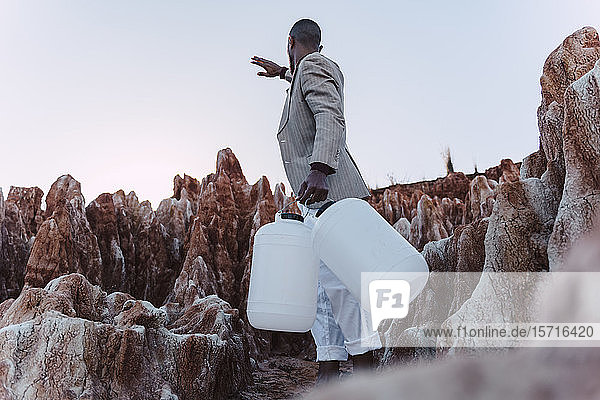 Junger Mann mit leerer Dose auf der Suche nach Wasser in unfruchtbarem Land