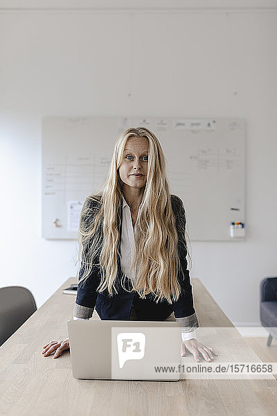 Porträt einer jungen Geschäftsfrau  die Yoga praktiziert  auf einem Schreibtisch im Büro