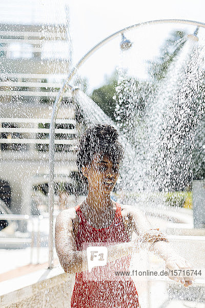 Junge Frau im roten Badeanzug duscht im Freien