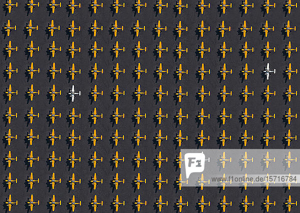 Aerial view of three white airplanes amid rows of only orange ones
