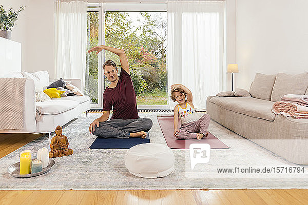 Father and daughter doing yoga together at home