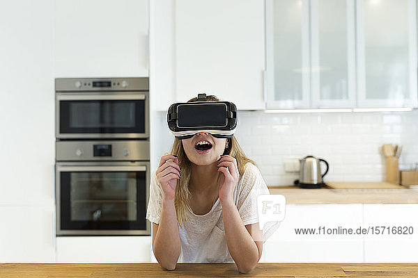 Female teenager in the kitchen with VR glasses