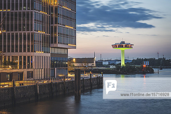Deutschland  Hamburg  Gebäude am Wasser in der Abenddämmerung mit Leuchtturm Null im Hintergrund