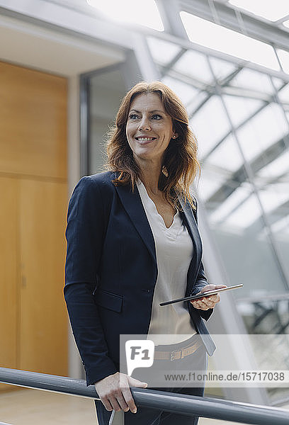 Selbstbewusste Geschäftsfrau hält ein Tablett in einem modernen Bürogebäude
