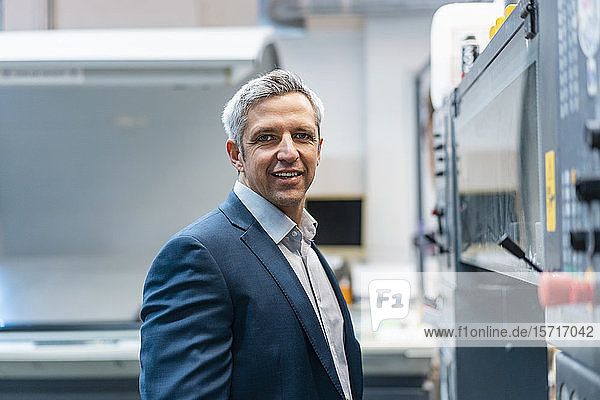 Portrait of a confident businessman at a machine in a factory