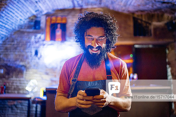 Young man  working in bar  using smartphone