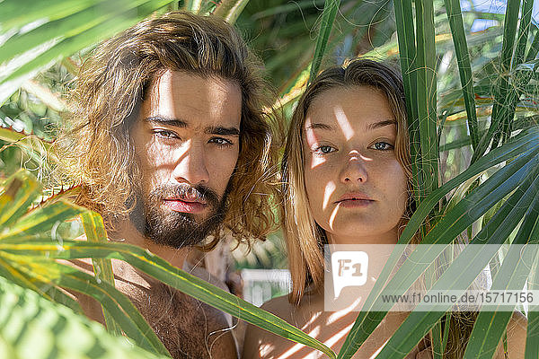 Porträt eines nackten jungen Paares zwischen Palmenblättern