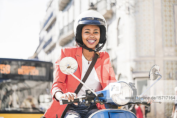 Porträt einer glücklichen jungen Frau auf einem Motorroller in der Stadt  Lissabon  Portugal