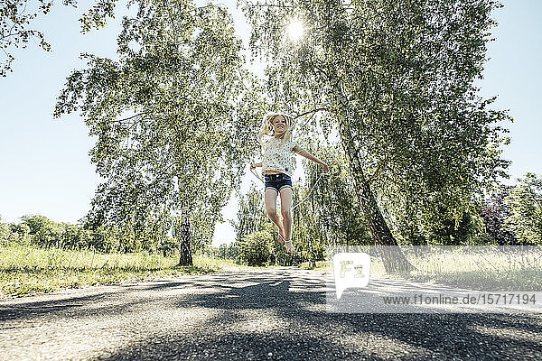 Glückliches Mädchen springt Seil auf einem Parkweg