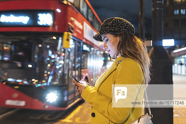Happy woman waiting for the bus in the city at night  London  Great Britain