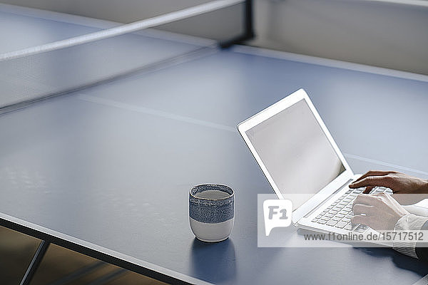 Nahaufnahme einer Geschäftsfrau mit Laptop auf einem Tischtennistisch im Büro