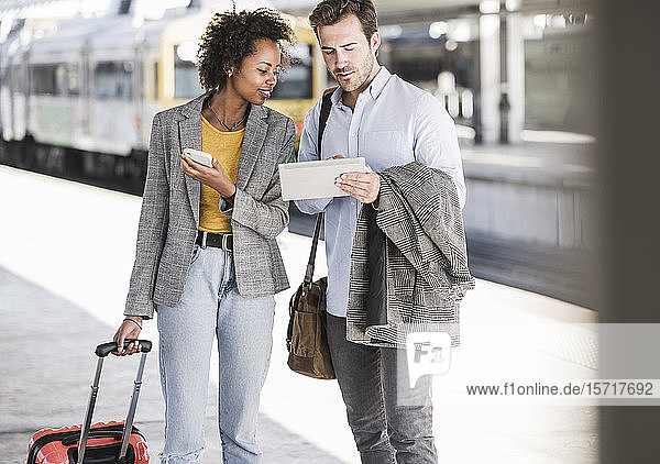 Young businessman and businesswoman using tablet together at the train station