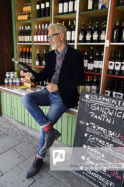 Mature man choosing bottle of wine at a wine shop