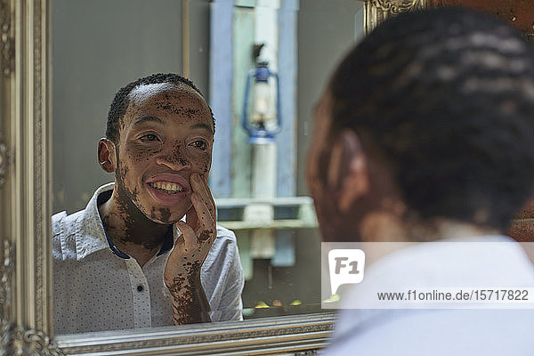 Junger Mann mit Vitiligo beim Blick in den Spiegel
