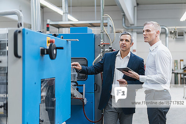 Zwei Geschäftsleute mit Tablette im Gespräch in einer Fabrik