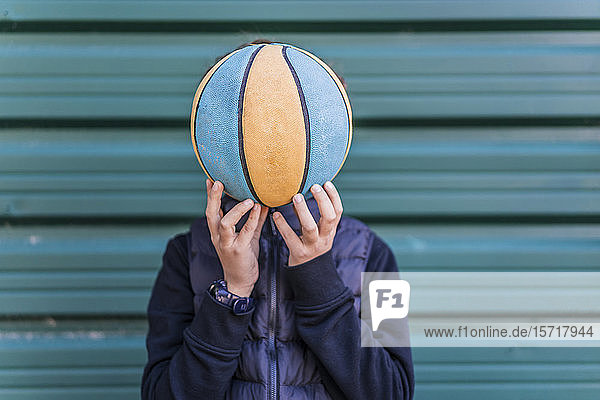 Junge bedeckt sein Gesicht mit einem Basketball