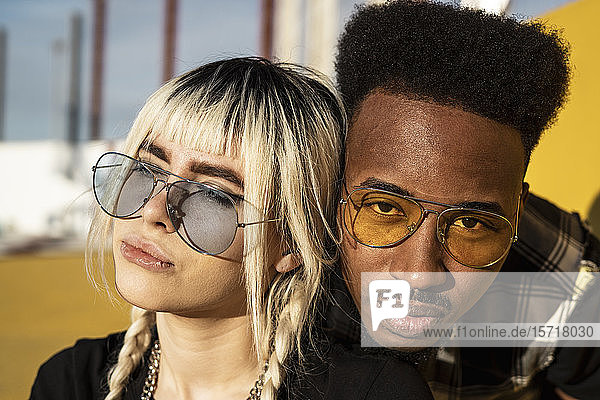 Portrait of young couple wearing coloured sunglasses