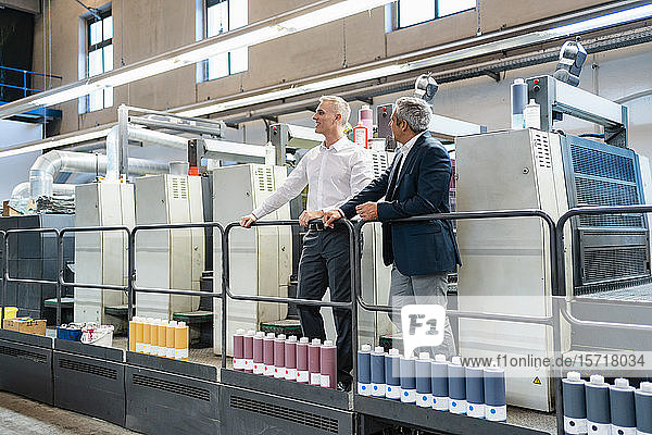 Two businessmen in a printing shop looking around