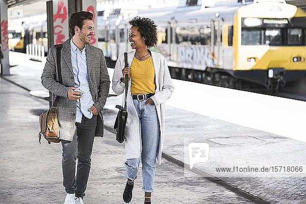 Happy young businessman and businesswoman walking and talking at the train station