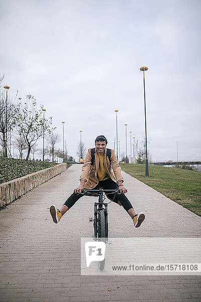 Verspielter junger Mann auf dem Fahrrad in der Stadt